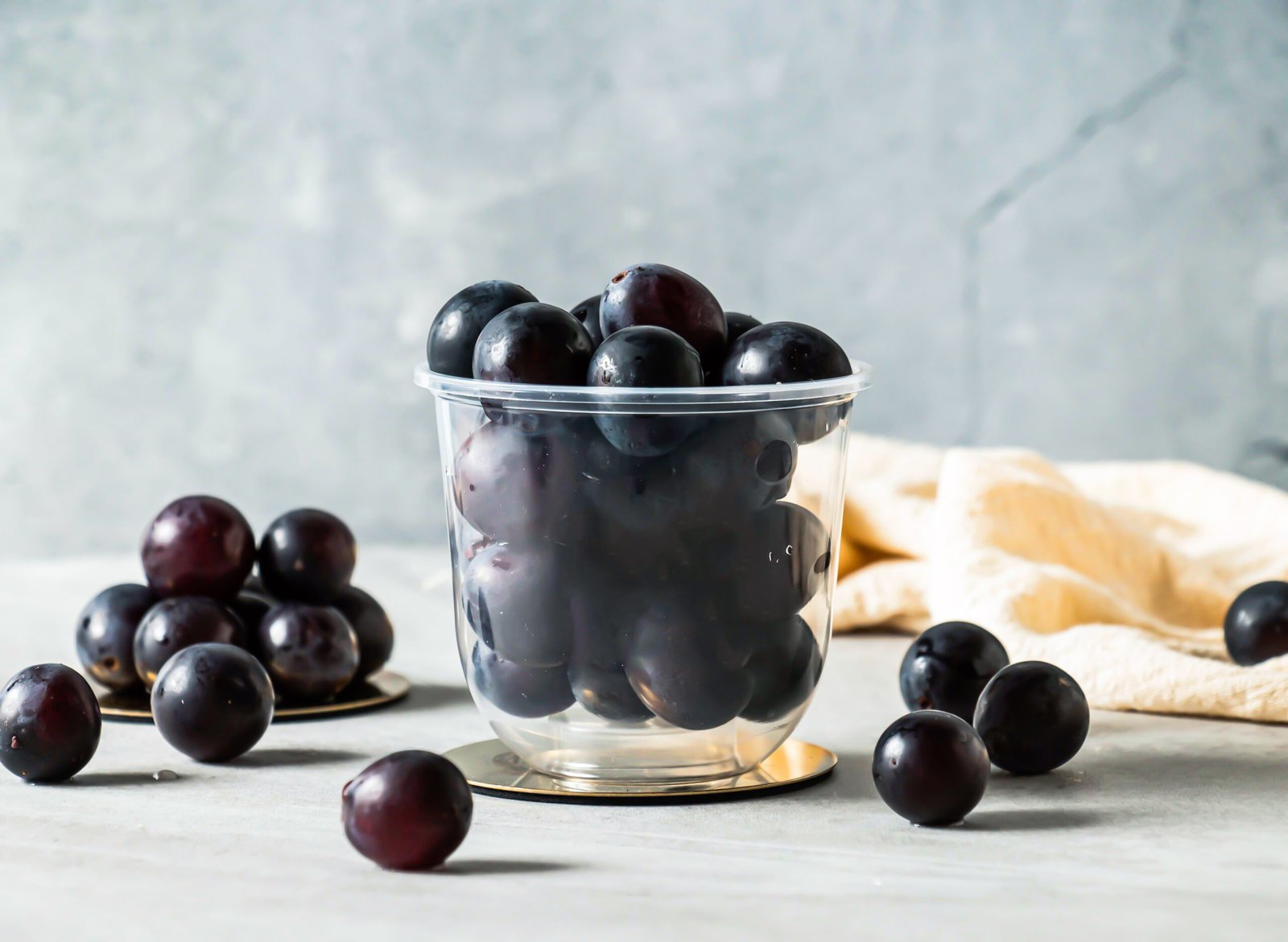 A glass bowl filled with fresh dark purple grapes on a rustic table.
